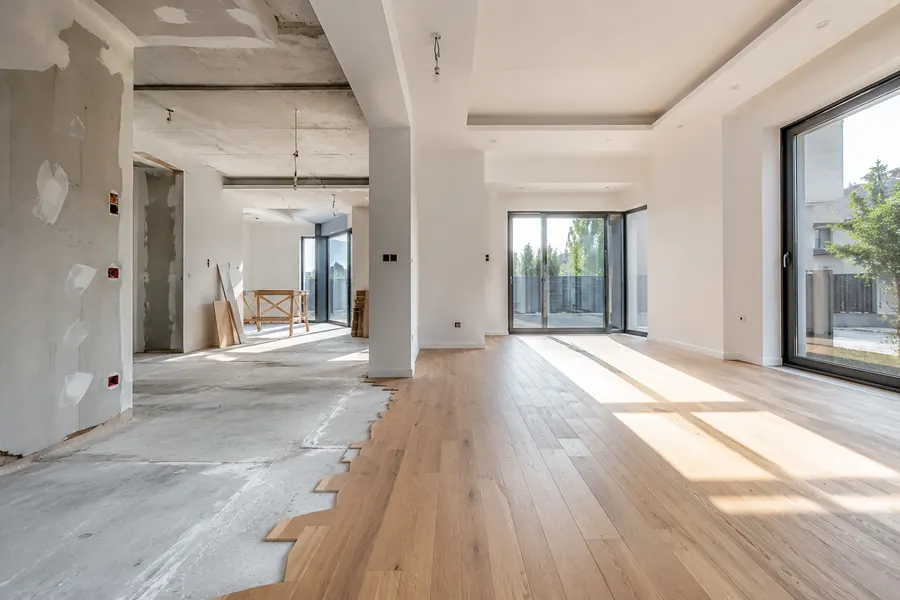 Wohnung während der Sanierung: links Rohbau mit offenem Estrich, rechts fertiger Eichenboden und verputzte Wände